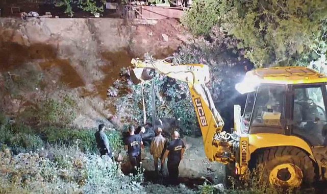 Düştüğü su kanalında çamura saplanan inek, kepçeyle kurtarıldı