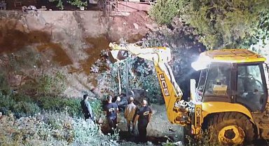 Düştüğü su kanalında çamura saplanan inek, kepçeyle kurtarıldı