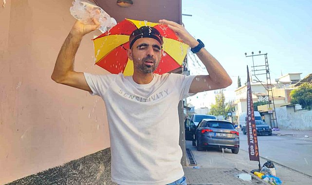 Aşırı sıcaklar nedeniyle kafasına taktığı şemsiye ile geziyor