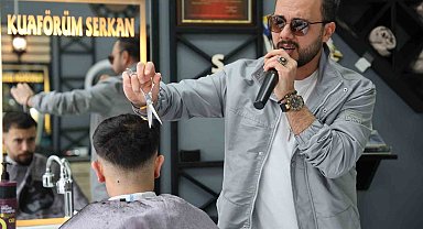 Bir elinde makas diğer elinde mikrofon