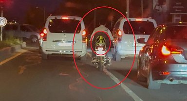 Motosiklet sürücüsü trafikte kaskı başına takması yerine arkasına bağladı