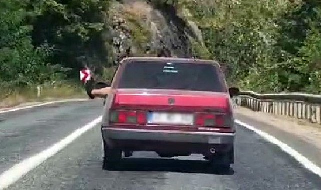 Ayaklarını camdan sarkıtarak trafiği tehlikeye attı