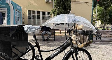 Bisiklet sepetindeki köpeğini yağmurdan şemsiye ile korudu