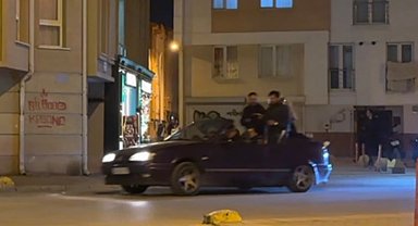Seyir halindeki otomobillin bagajına ters oturan şahıs dikkat çekti